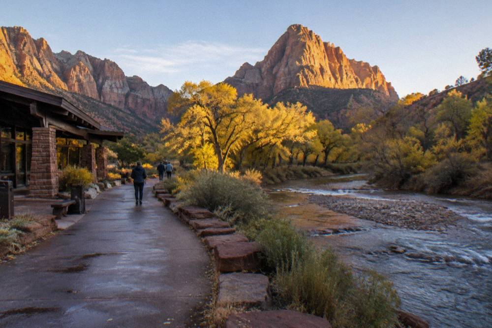 Canyon walls rising above a tree-lined river corridor in morning light