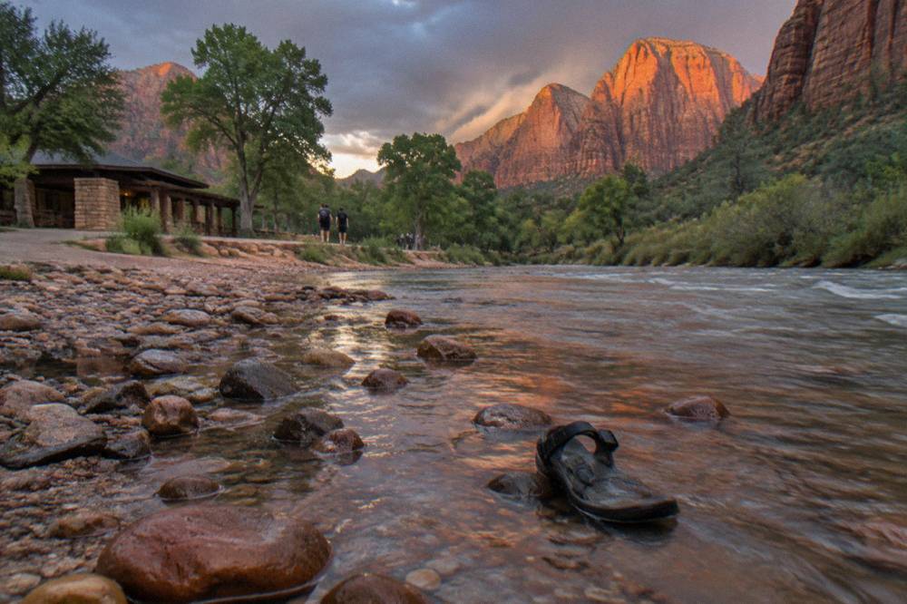 Golden light on tall canyon walls above a shallow river and tree line