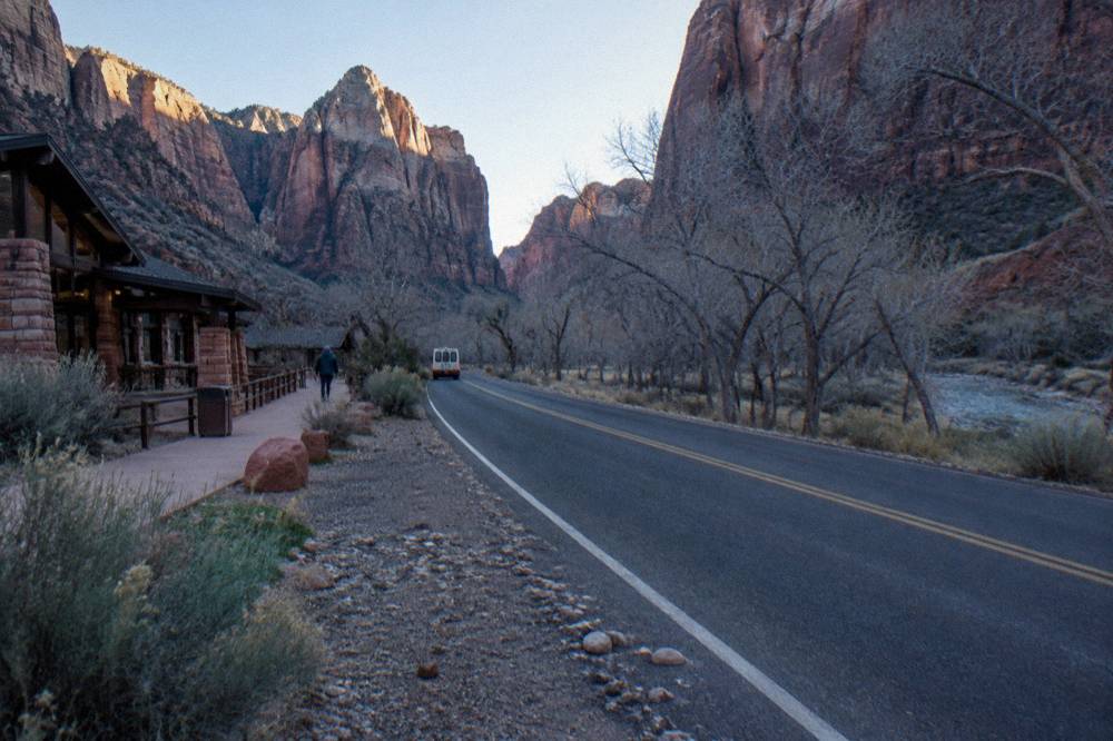 A quiet canyon road in early morning light with tall sandstone walls on both sides