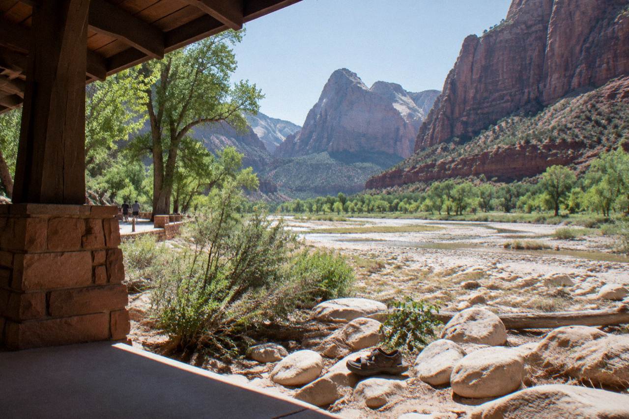 Red rock canyon walls rising above a dry river valley under a wide morning sky
