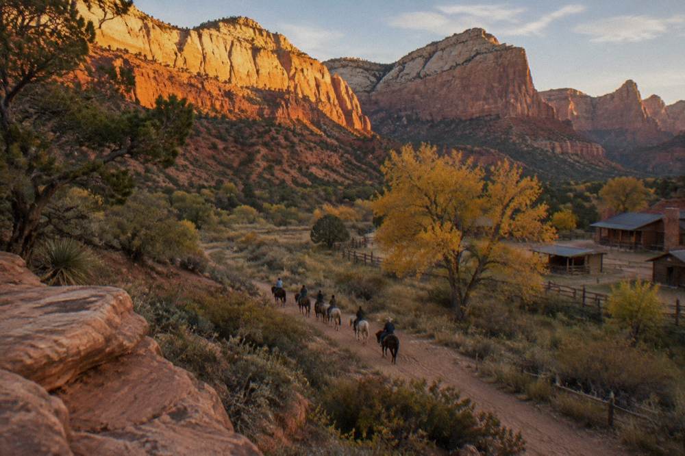 Golden evening light on layered red rock cliffs above a desert riding trail