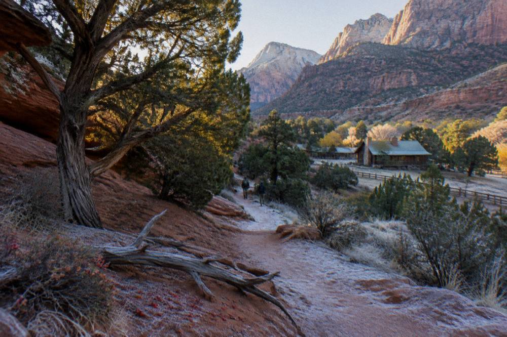 A sandy trail winding between low red rock ledges and scattered juniper trees