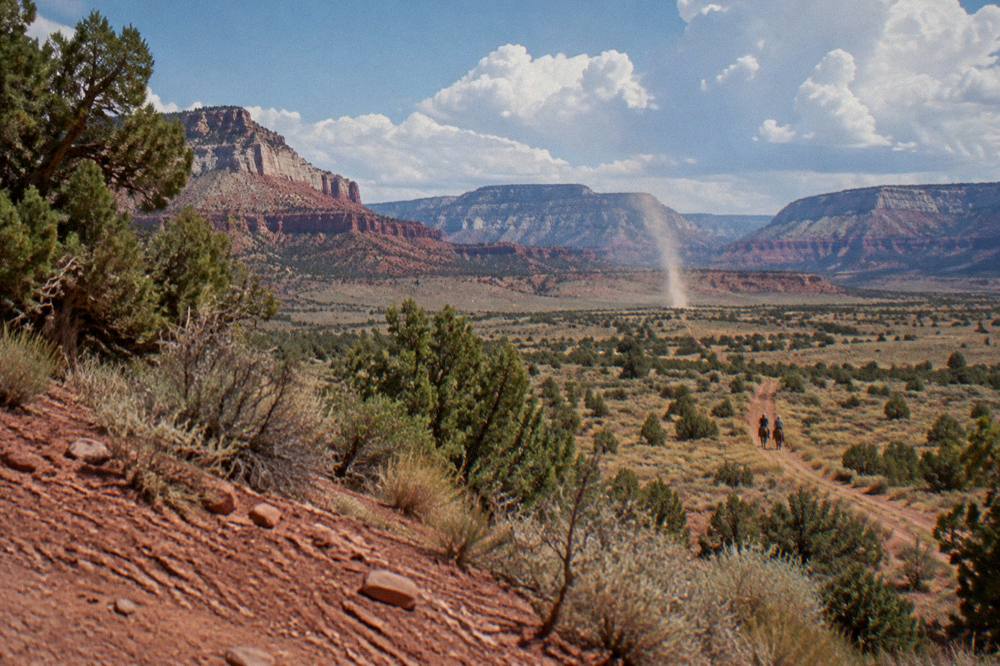 Wide high desert plain with mesas on the horizon under scattered clouds