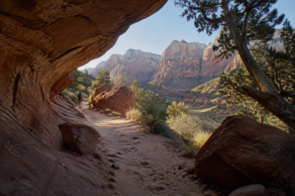 Sandy desert trail winding between red rock formations under morning light