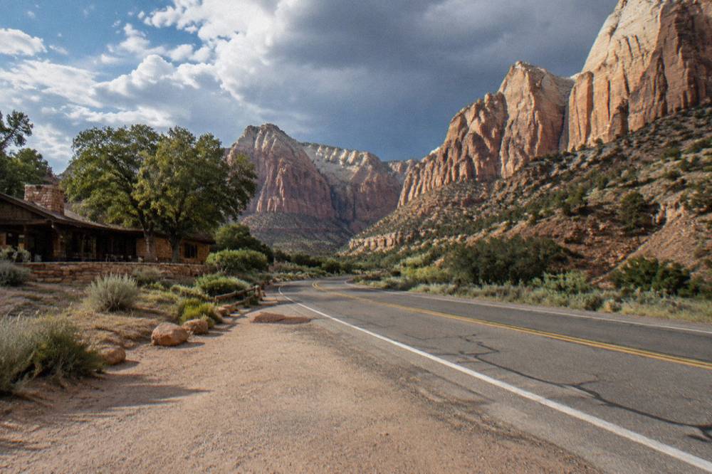 Empty desert highway curving toward tall sandstone cliffs in southern Utah