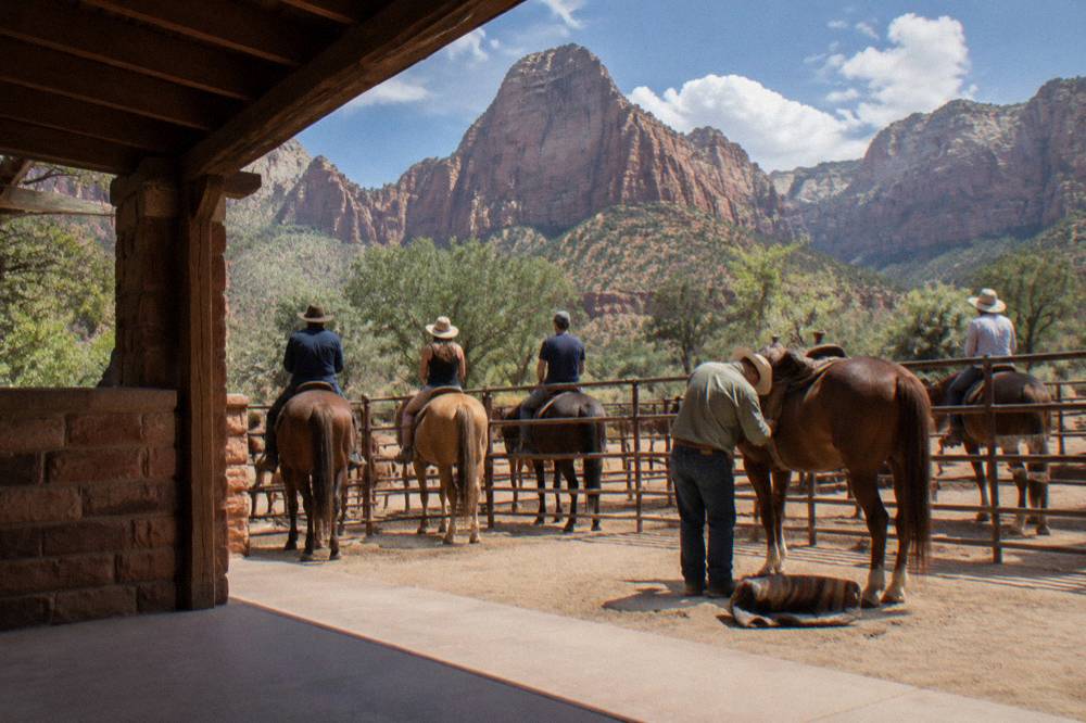 Riders mounted on horses at a corral near tall canyon walls waiting to depart