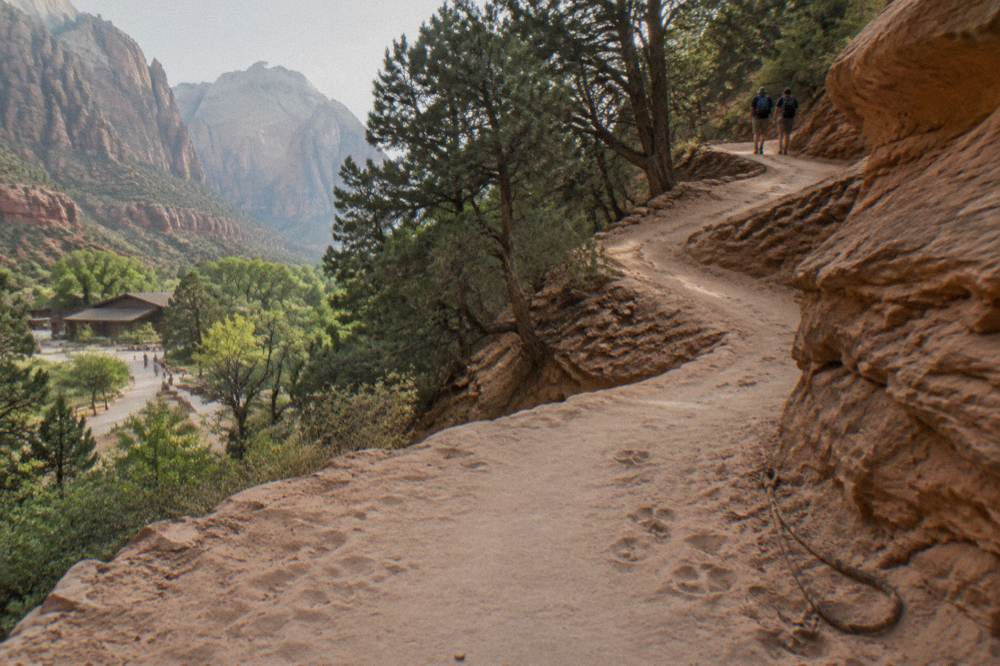 A horse trail switchbacking up a sandy slope between junipers and rock formations