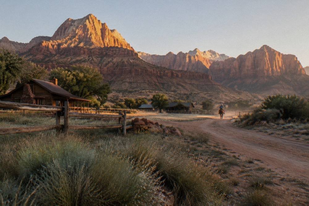 Golden morning light on layered red rock mesas above dry grassland