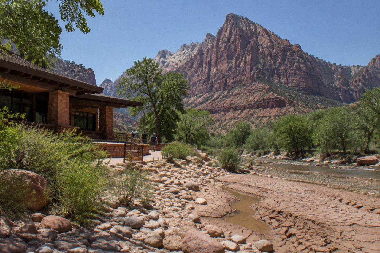 Red rock cliffs rising above dry canyon country under a clear summer sky
