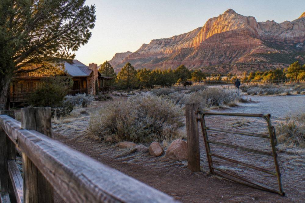 Golden late-afternoon light on layered red rock formations above open rangeland