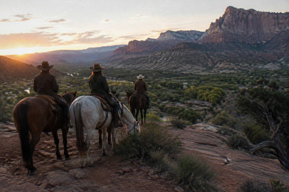 Riders pausing at a sandstone overlook in low evening light