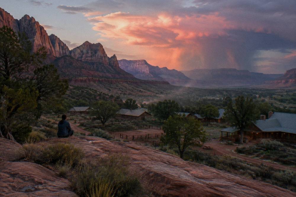 Storm clouds catching pink light above a wide desert valley near Zion