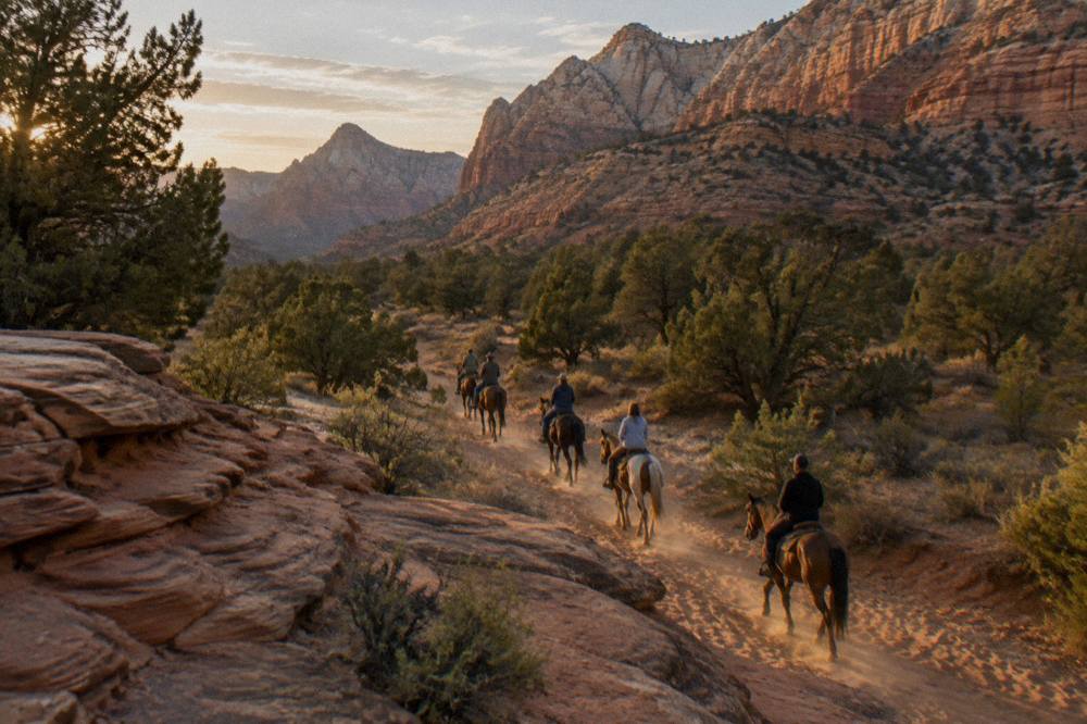 Golden evening light on layered rock cliffs above a desert riding trail